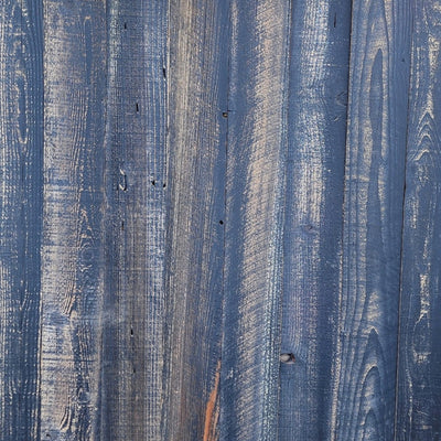 Black finish reclaimed redwood S3S wall planks laid flat, grain and saw marks visible through the pigment